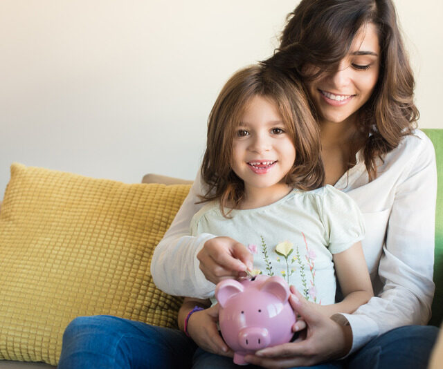 Mother and daughter putting coins into piggy bank